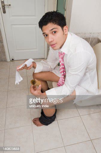 Man Sitting On A Toilet Seat And Showing A Toilet Paper High Res Stock