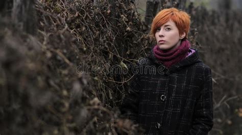 Sweet Red Haired Girl In A Black Coat And Purple Knitted Scarf Is