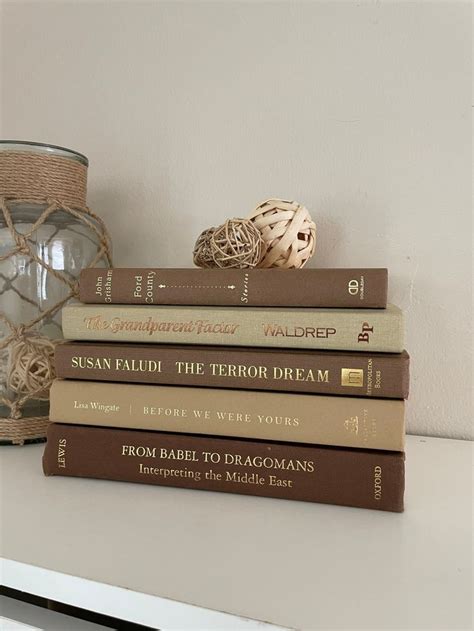stack  books sitting  top   white table    glass vase