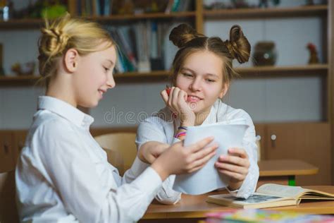 Teen Girls In The School Library Or Classroom Discussing What They Are