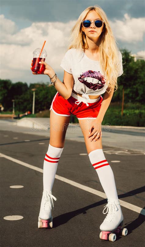 beautiful blonde girl posing on a vintage roller skates in pink shorts