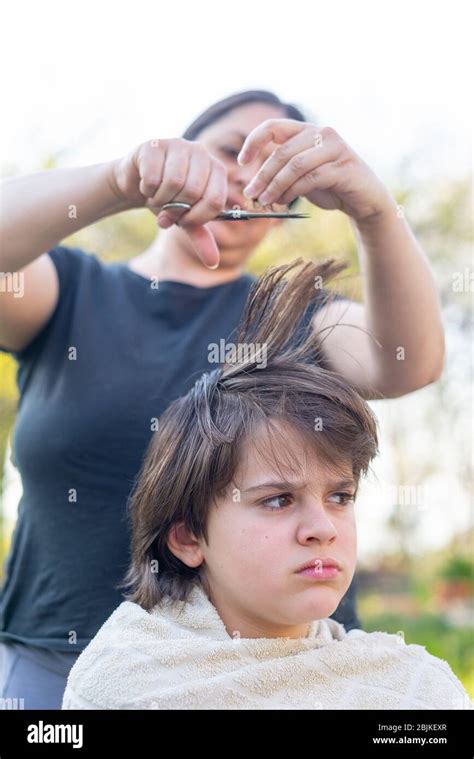 Mother Cuts Her Son S Hair In The Garden At Home The Mother Is A