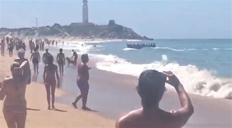 Stunned Tourists Look On As Dozens Migrants Land On Packed