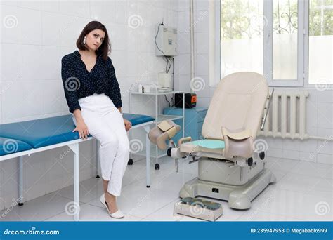 Upset Young Woman In Front Of Gynecological Chair At Clinic Stock Image