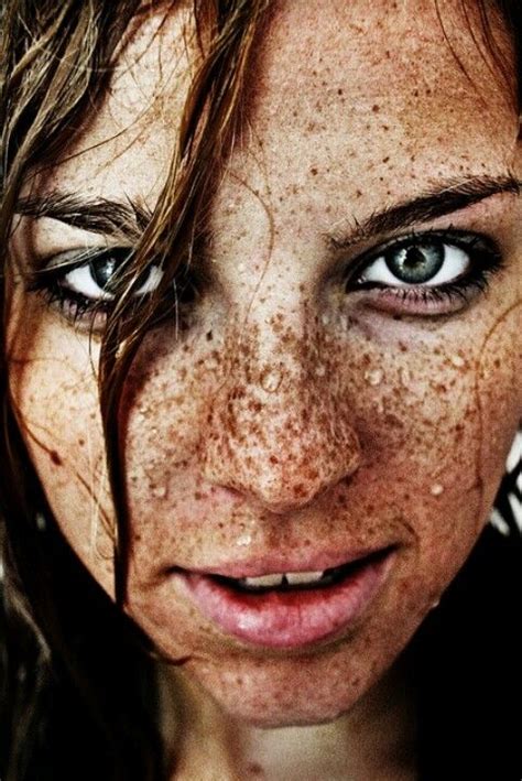 A Woman With Freckles On Her Face And Blue Eyes Looking At The Camera