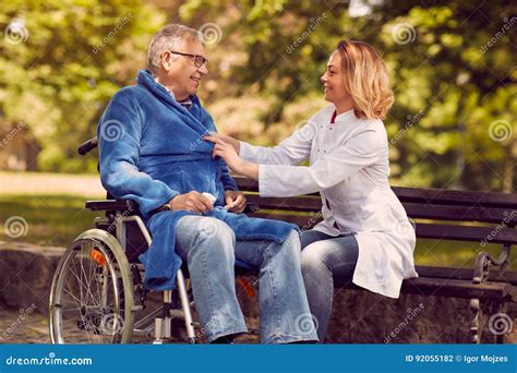 caregiver nurse helping disabled senior patient in wheelchair stock