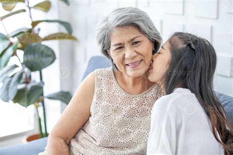 asian grandma and granddaughter hugged with happy mood on the sofa in