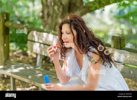 Beautiful Mature Adult Woman Playing In The Park Blowing Soap Bubbles