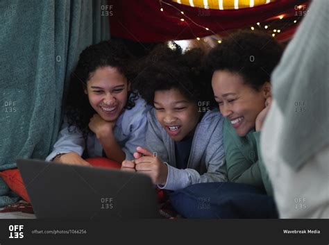 mixed race lesbian couple and daughter lying in blanket fort using