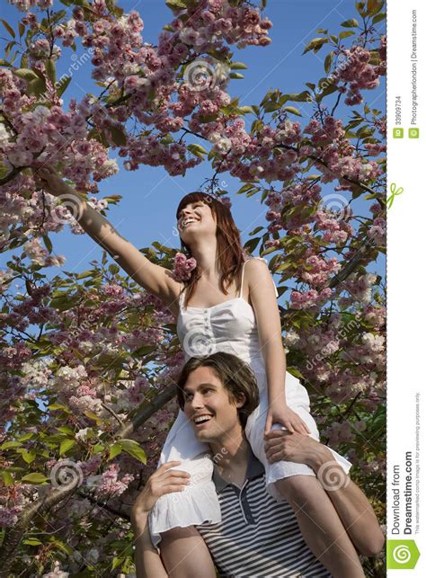 Woman Plucking Flowers While Sitting On Man S Shoulders
