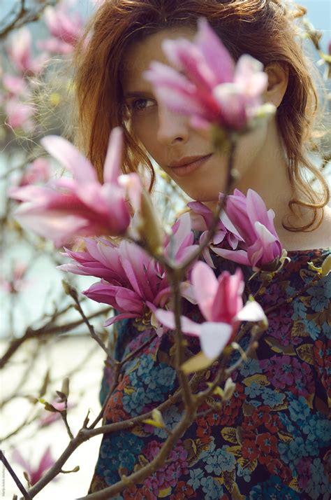 beautiful redhead girl in pink spring flowers by stocksy contributor