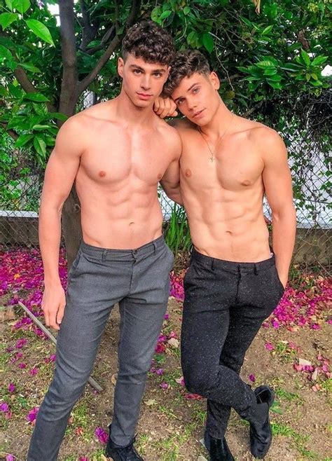 Two Men Standing Next To Each Other In Front Of Trees And Purple