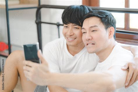 Happy Asian Gay Couple Use Mobile Phone Video Call Or Selfie On Bed