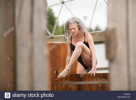 Mature Woman Stepping Out Of Hot Tub At Eco Retreat Stock