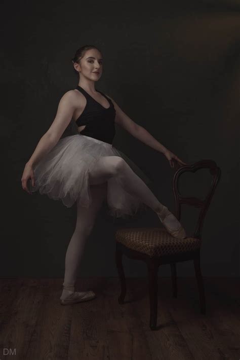 photograph of a ballerina wearing a tutu and posing with a chair