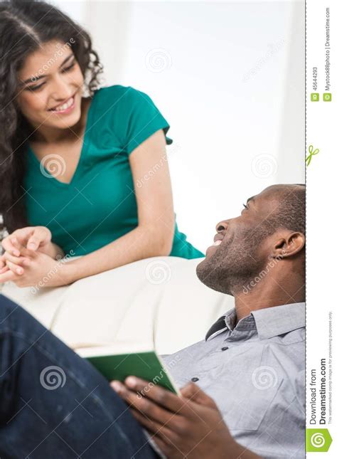 couple in living room talking while sitting on sofa stock