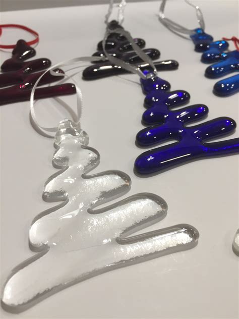 Several Different Colored Glass Ornaments Hanging From Hooks On A White