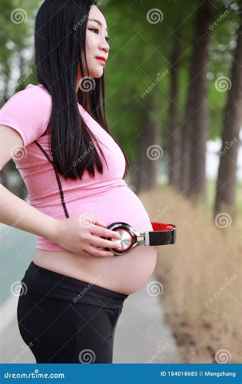 Close Up Asian Chinese Pregnant Woman In Yoga Dress Hands With Earphone