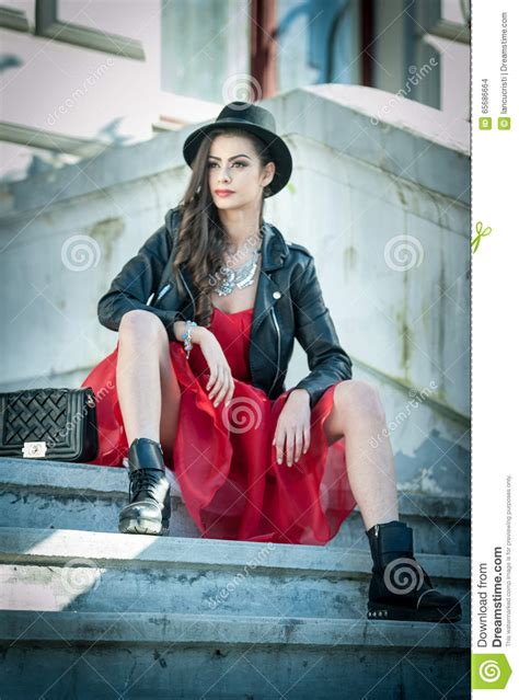 beautiful woman with black hat red dress and boots posing