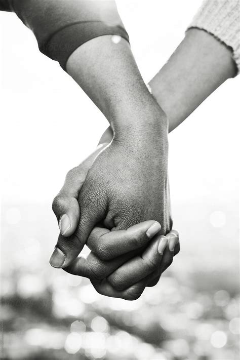 closeup of couple holding hands outside black and white photo stocksy united