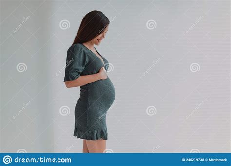 Beautiful Pregnant Young Asian Woman Looking Down At Her Belly For
