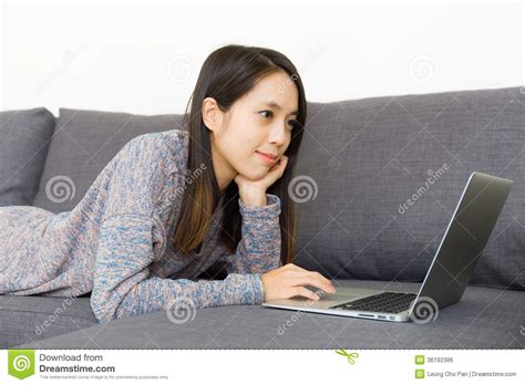 Asian Woman Using Laptop Computer On Sofa Royalty Free