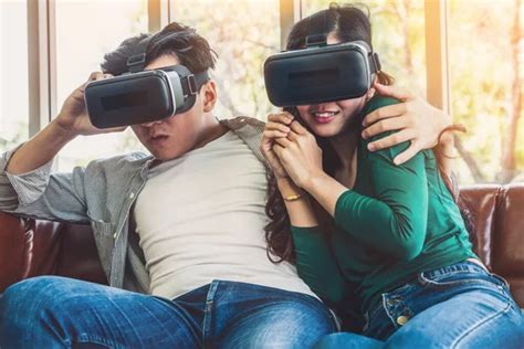 Happy Couple Watching Video In Virtual Reality Vr Headset In Living