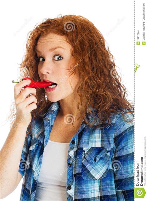 redhead woman taking bite of spicy red pepper stock images image