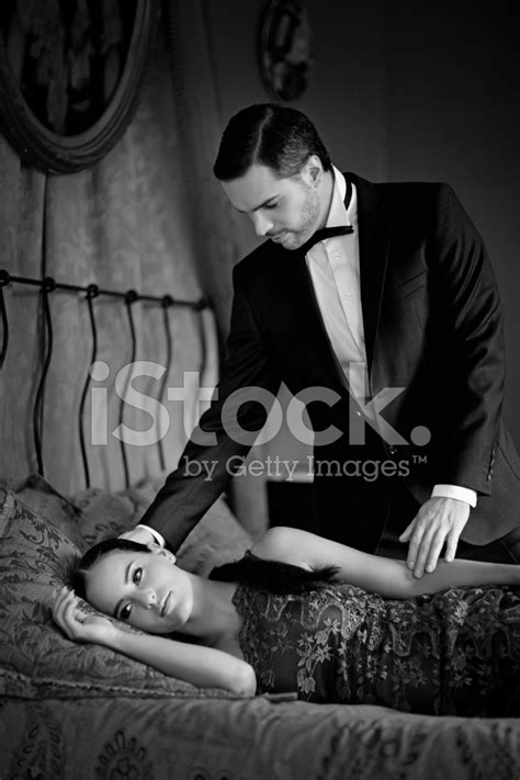 Well Dressed Man Next To Laying Down On Bed Woman Stock