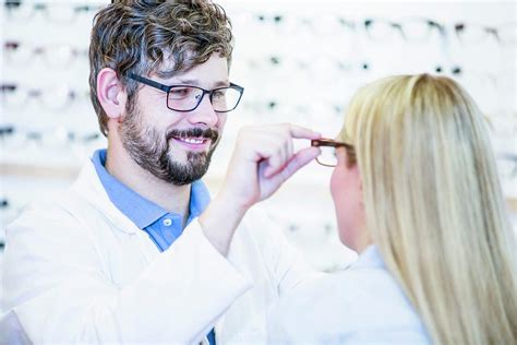 Optometrist Trying Glasses On Woman Photograph By Science Photo Library