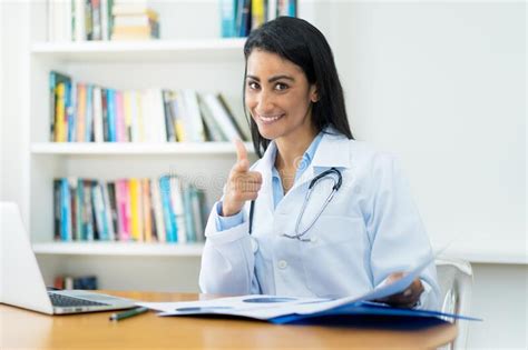 Laughing Latin American Female Gynecologist At Desk At Work Stock Image