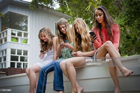 4 teen girls togetheralone on cell phones high res stock