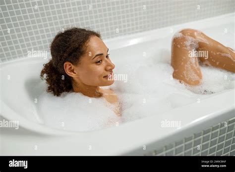 Smiling Afro American Woman Takes Bubble Bath In Bathtub Spa Wellness