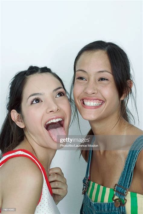 Two Young Female Friends One Sticking Tongue Out The Other Laughing