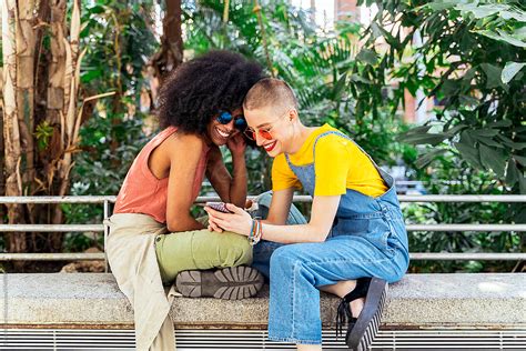 beautiful lesbian couple using a mobile in the street del colaborador