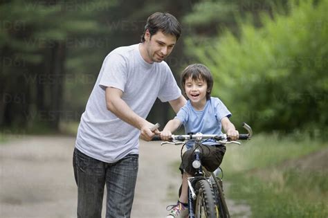 father teaching  son  ride  bicycle stock photo