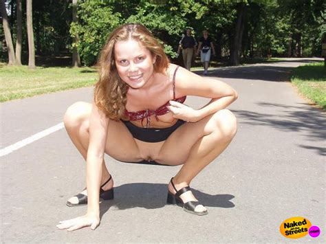 crazy teen slut flashing her tits and pussy by crouching down right in the park