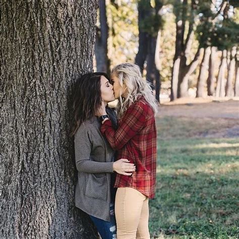 Two Women Kissing Each Other Next To A Tree