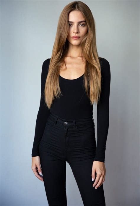 woman  long hair standing  front   gray wall wearing black