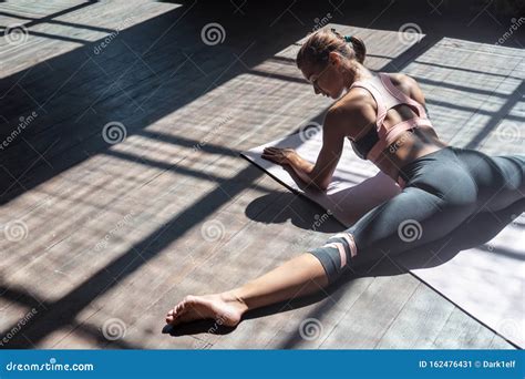 Sporty Young Woman Stretching Legs Split Sit On Mat In Gym Stock Image