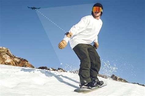 man riding  snowboard   side   snow covered slope   blue sky