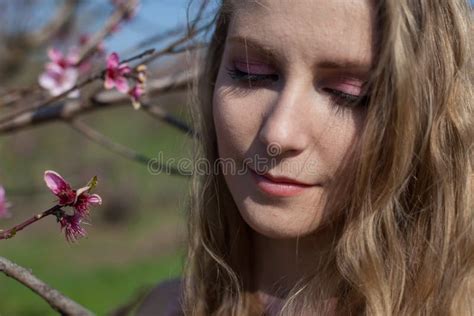 Beautiful Blonde Woman In Pink Dress Walks Through The Flowering Garden