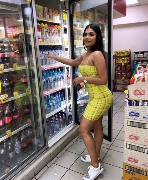a woman standing in front of a refrigerator filled with water and sodas