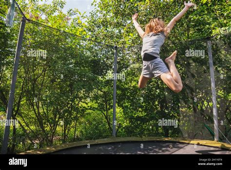 Preteen Girl Having Fun Bouncing On A Trampoline In A Backyard On A