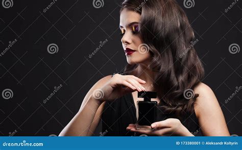Attractive Young Brunette Woman And A Bottle With A New Fragrance Use