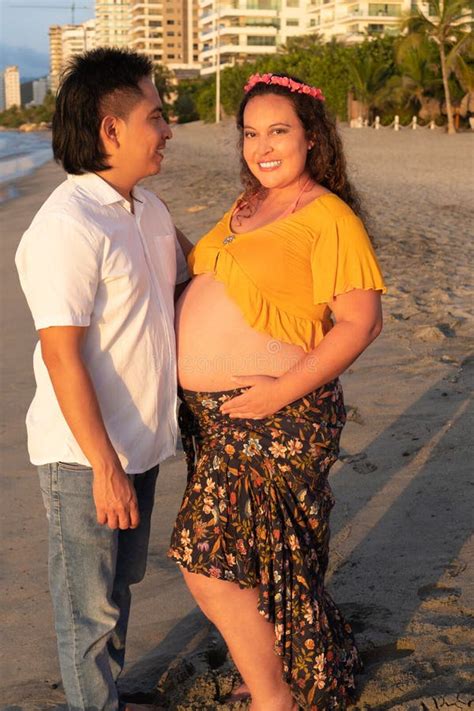 Portrait Of Pregnant Latina Woman And Her Husband Embracing On The
