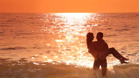 loving teen couple have fun on the beach at sunset stock