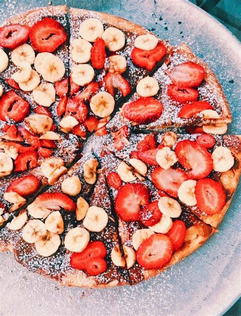 a pizza covered in sliced bananas and strawberries
