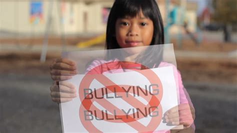 a cute asian girl holds up a no bullying sign on the school playground stock footage video