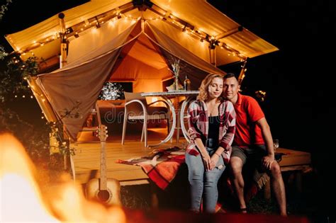 happy lovely couple relaxing in glamping on evening near cozy bonfire
